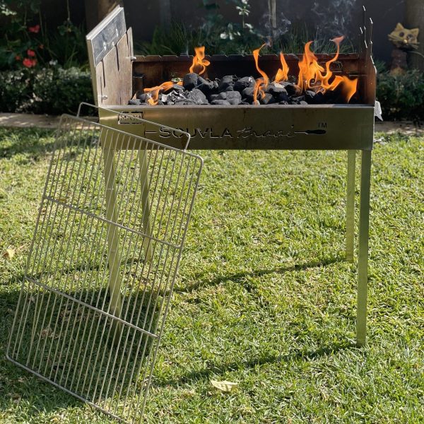Flat grill next to souvla braai with hot coals in the garden
