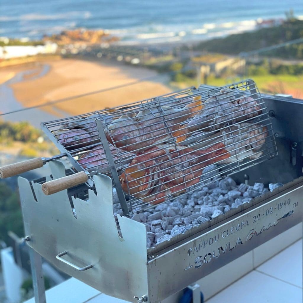 Fish souvla being cooked on a souvla braai in a rotating grill